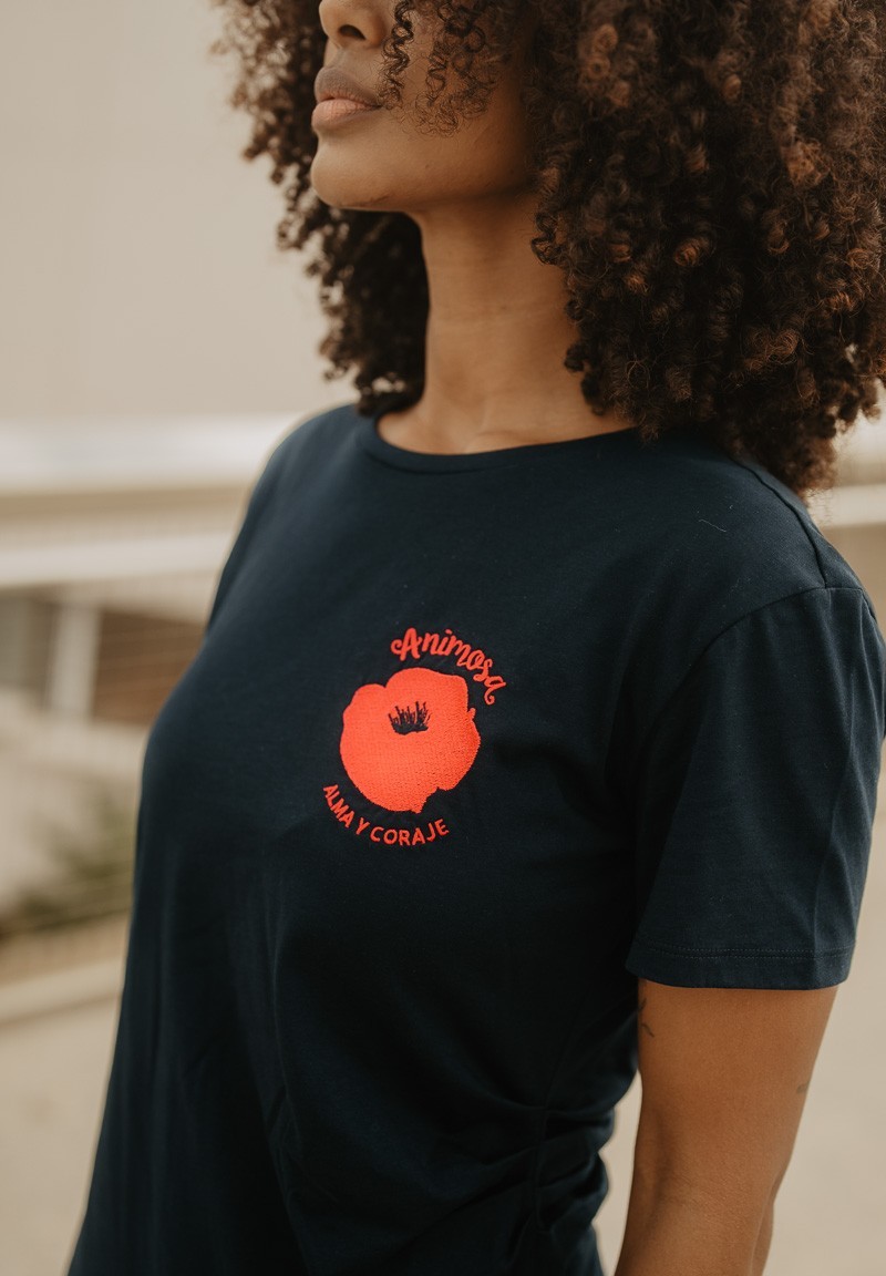 Camiseta negra de manga corta con amapola en el pecho, detalle del bordado.
