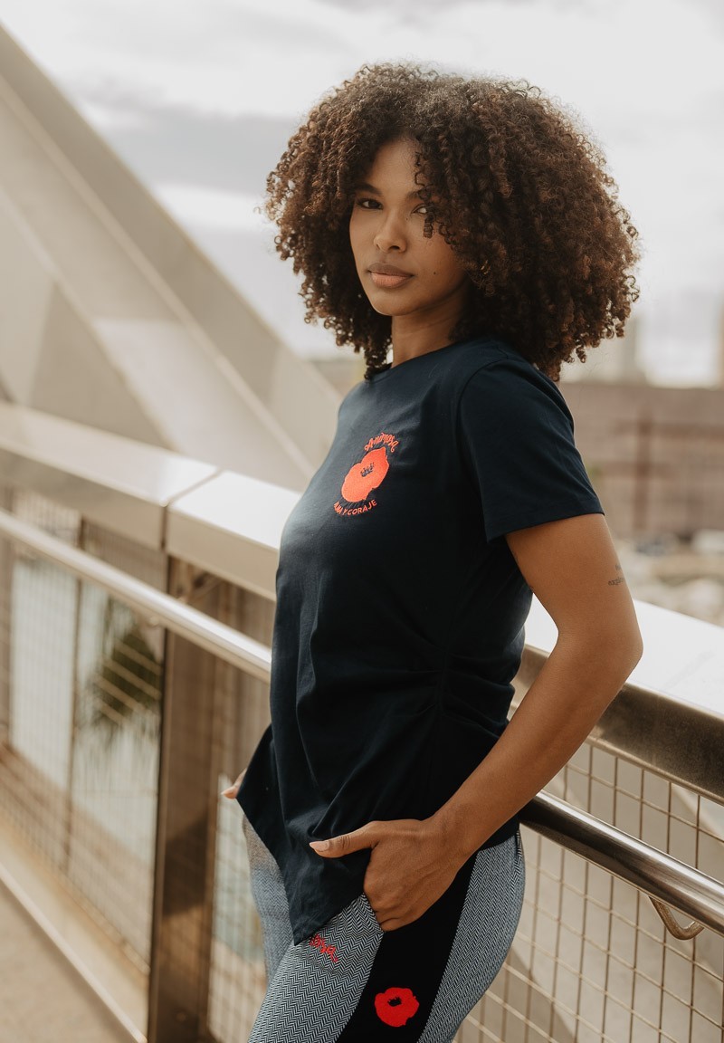 Camiseta negra de manga corta con amapola en el pecho, vista lateral.